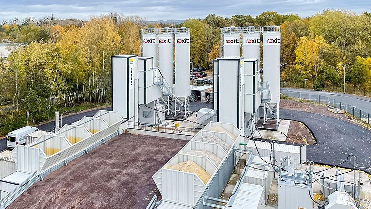 Mobile concrete mixing plant with silos, aggregate boxes and technical containers to supply concrete for the construction of a microchip factory in an industrial environment