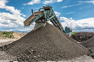 Förderanlage transportiert aufbereitetes Gesteins‑ bzw. Recyclingmaterial auf einen großen Materialhaufen in einer industriellen Anlage