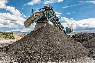 Förderanlage transportiert aufbereitetes Gesteins‑ bzw. Recyclingmaterial auf einen großen Materialhaufen in einer industriellen Anlage