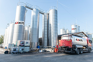 Industrial plant for in-house emulsion production with several storage tanks and a tanker for filling and delivering bitumen emulsions.