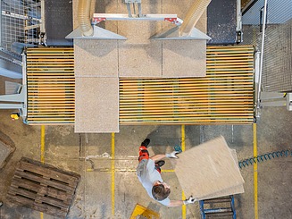 Insulation boards made of natural fibres are picked up manually from a conveyor belt in a production plant and processed further.