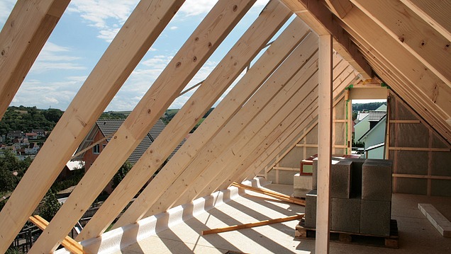 Roof construction made of wood with visible rafters and structural elements in the interior of a building in the finished state