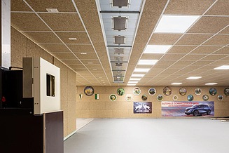 Interior with ceiling and wall surfaces made of fibre-based building panels, integrated into a grid ceiling system with lighting and ventilation elements.