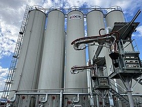 Moderne Siloanlagen und Anlagentechnik für polymermodifizierte Bitumen am roxit Standort Planá vor blauem Himmel mit Wolken.