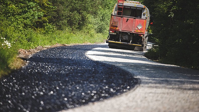 Application of a bituminous separating or protective layer on a traffic surface in civil engineering, carried out with a spray vehicle on a narrow road.