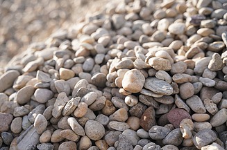 Nahaufnahme von Kies und kleinen Steinen mit unterschiedlichen Farben, Formen und Korngrößen in einem Materialhaufen.