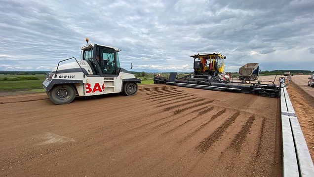 Road construction machinery and a roller being used to compact an unbound base course on a construction site in a rural area