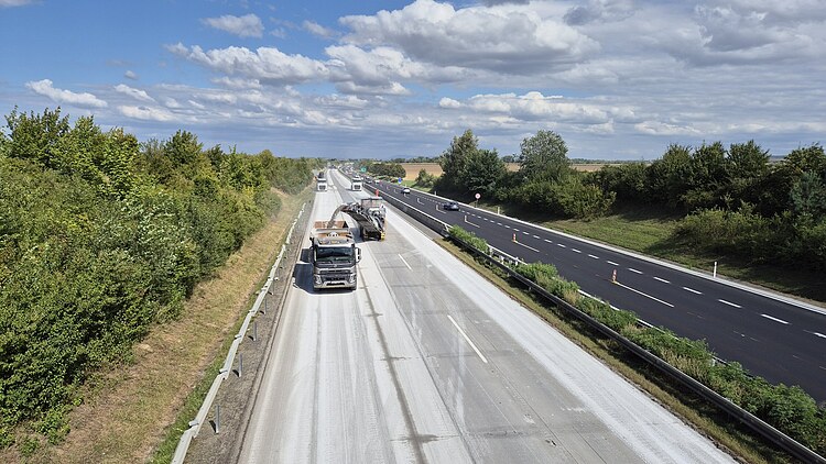 Motorway construction site on the D1 in the Czech Republic with road milling machine and lorry removing the carriageway; traffic continues to move in parallel