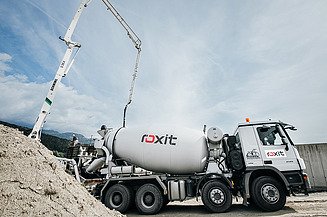 A concrete mixer truck delivers fresh concrete to a building site, whilst a concrete pump feeds the concrete via a boom to the point of placement.