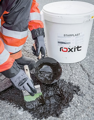 Application of a bituminous separating or protective layer on a traffic surface in civil engineering, carried out with a spray vehicle on a narrow road.
