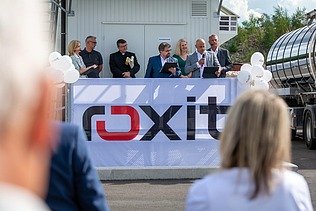 Festveranstaltung vor einer roxit-Anlage am Standort Planá: Mehrere Personen stehen auf einer Bühne und sprechen zu den Gästen. Im Vordergrund ist ein großes roxit-Banner zu sehen.