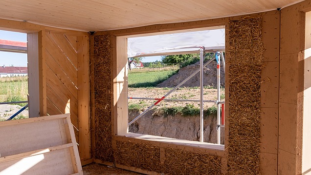 Interior of a house under construction with timber frame construction and visible insulation made of natural materials such as straw in the wall areas