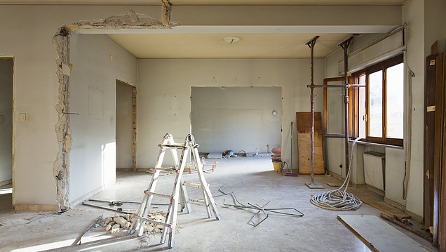 The interior of a flat undergoing renovation, with exposed walls, ceiling and floor, as well as building tools and pipes