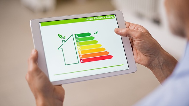 Hands holding a tablet on which an energy efficiency scale from A to G is displayed for a building
