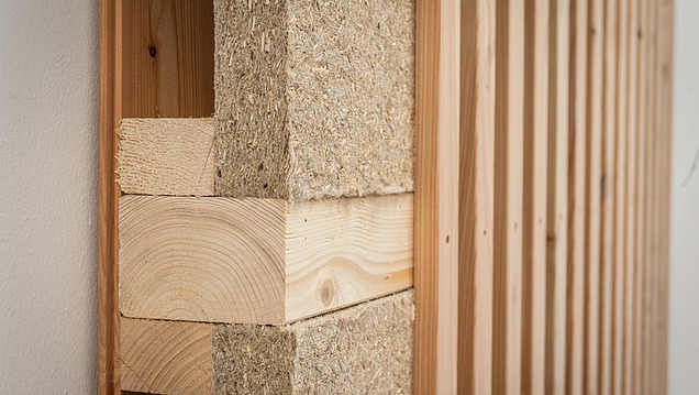 Detailed view of a timber construction element with visible timber construction and natural fibre-based insulation or absorber panels in between.
