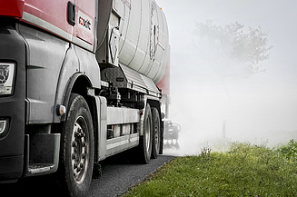 Tanker sprays milk of lime or hydrated lime along a carriageway, creating a visible layer of mist