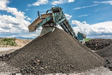 Conveyor system transports processed rock or recycling material to a large pile of material in an industrial plant